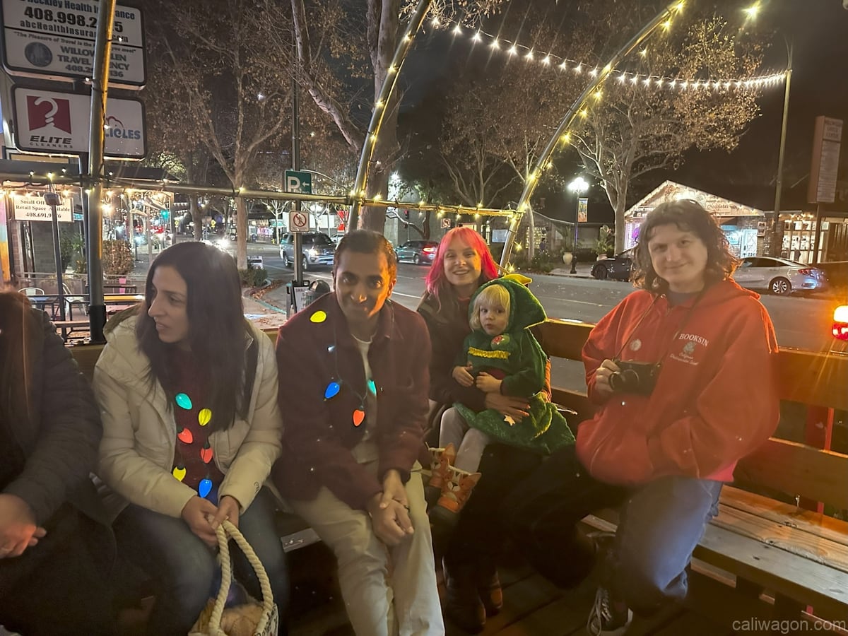 Riders aboard the Cali Wagon under lit hoops on a decorated Willow Glen street, December 2024 (photo 14 of 81)
