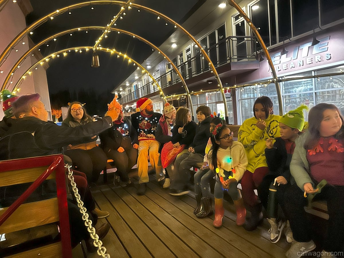 Riders aboard the Cali Wagon under lit hoops on a decorated Willow Glen street, December 2024 (photo 19 of 81)