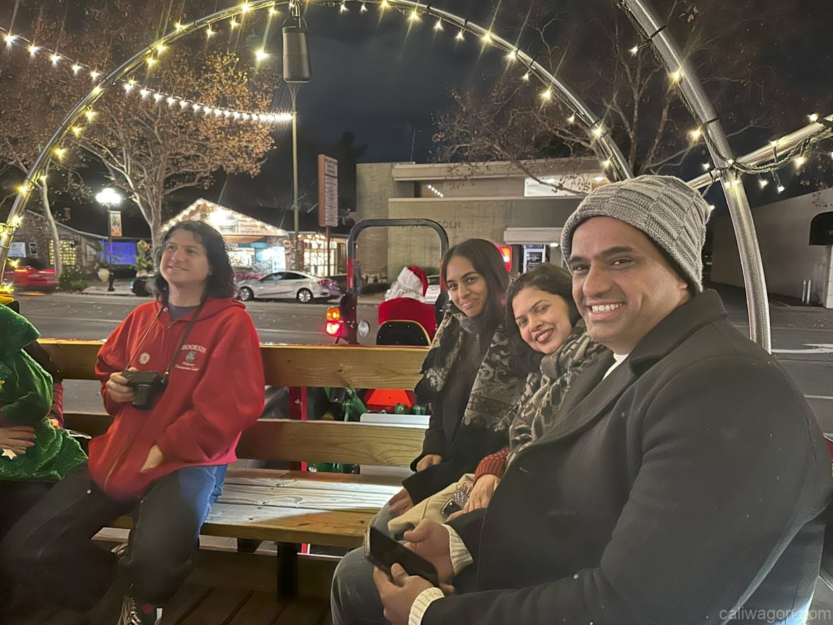 Riders aboard the Cali Wagon under lit hoops on a decorated Willow Glen street, December 2024 (photo 16 of 81)