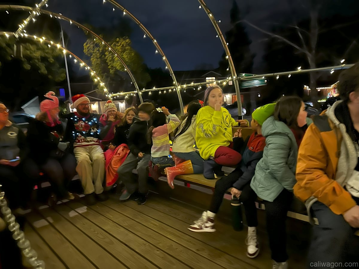 Riders aboard the Cali Wagon under lit hoops on a decorated Willow Glen street, December 2024 (photo 18 of 81)