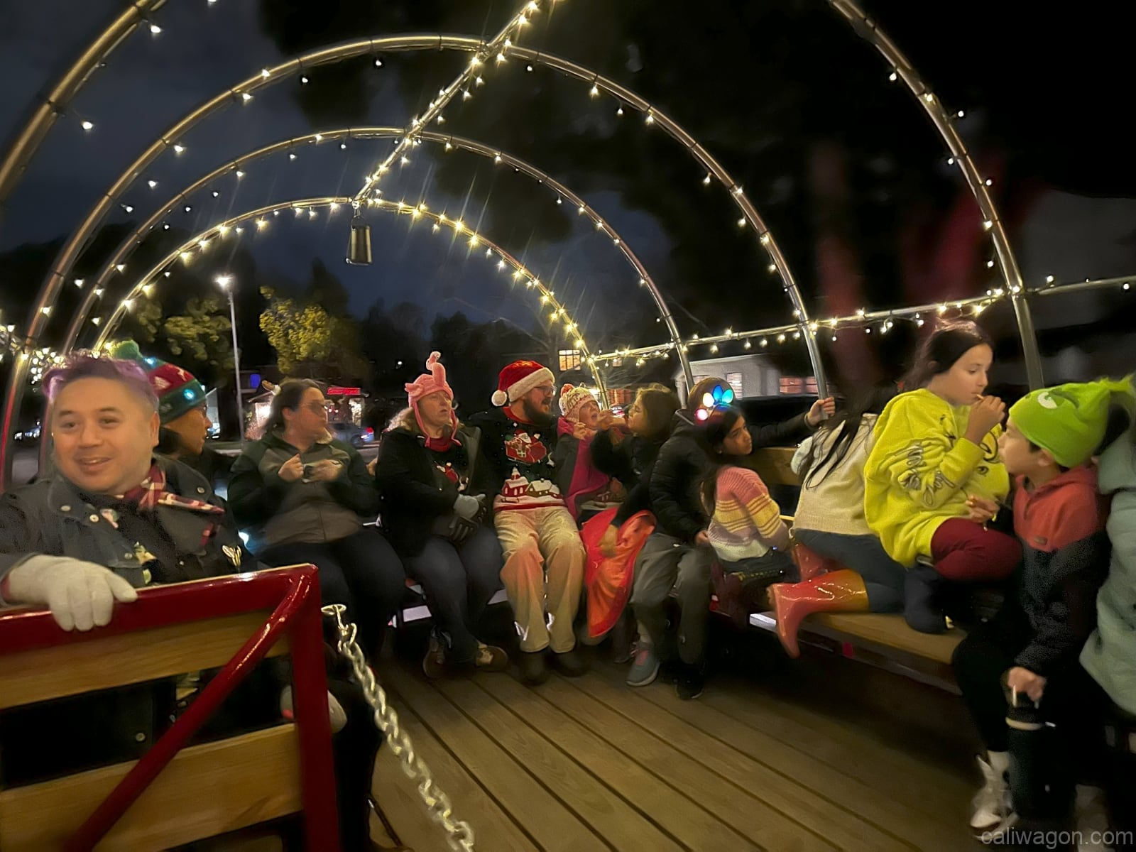 Riders aboard the Cali Wagon under lit hoops on a decorated Willow Glen street, December 2024 (photo 17 of 81)