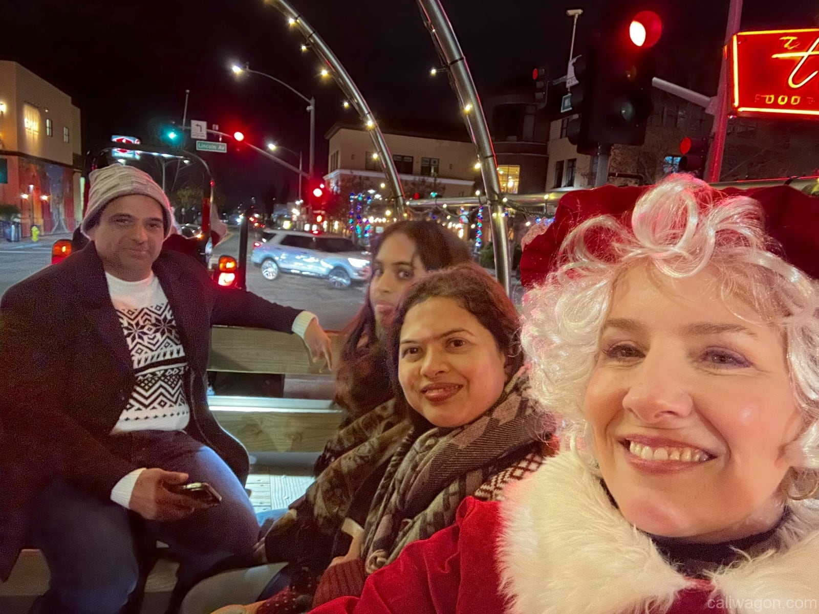 Riders aboard the Cali Wagon under lit hoops on a decorated Willow Glen street, December 2024 (photo 23 of 81)