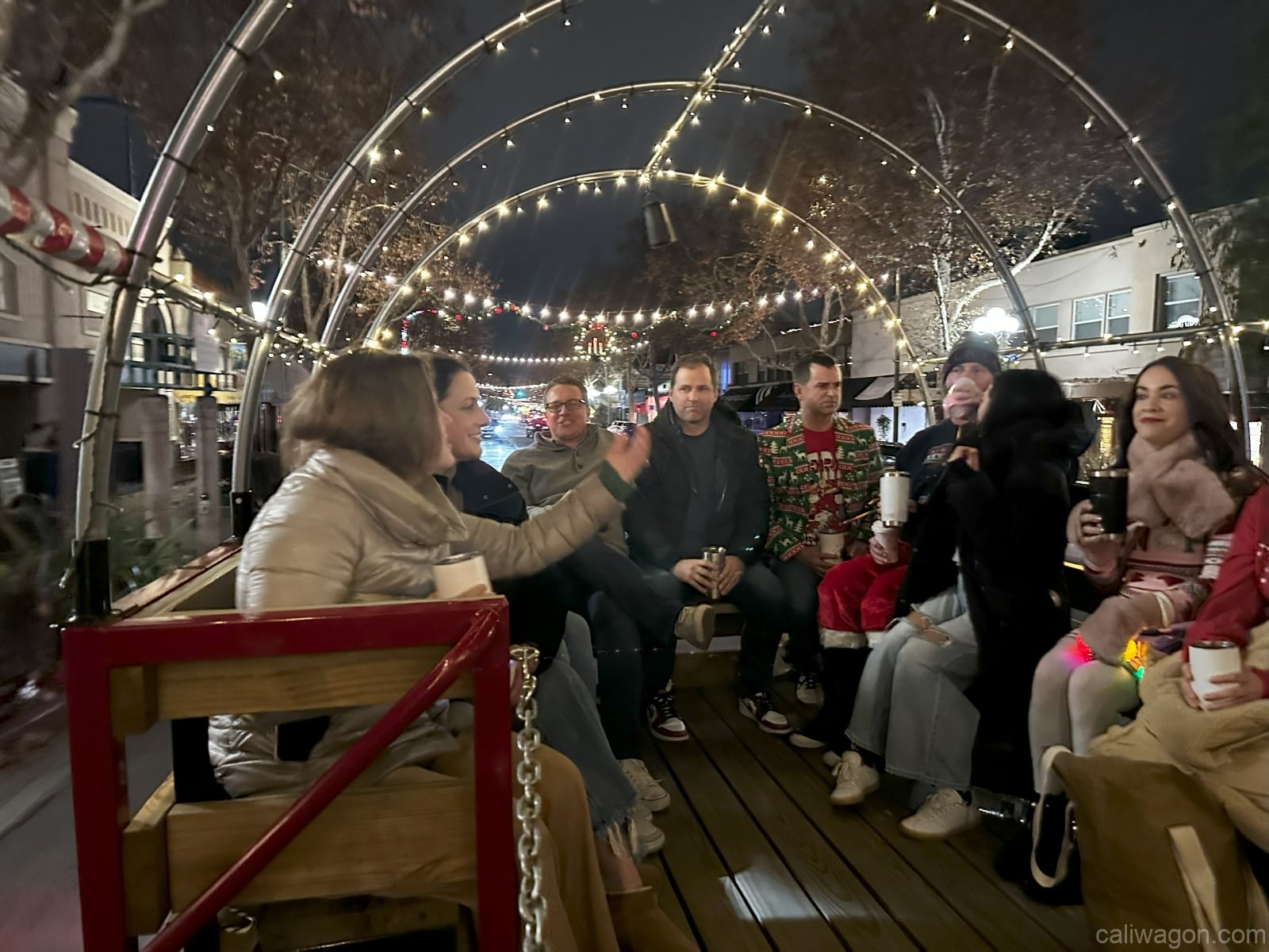 Riders aboard the Cali Wagon under lit hoops on a decorated Willow Glen street, December 2024 (photo 4 of 81)
