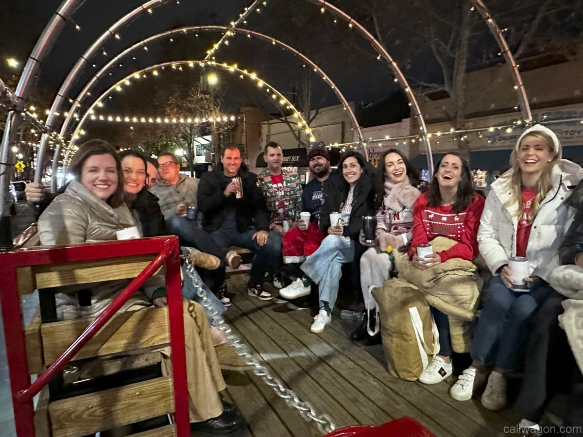 Riders aboard the Cali Wagon under lit hoops on a decorated Willow Glen street, December 2024 (photo 2 of 81)
