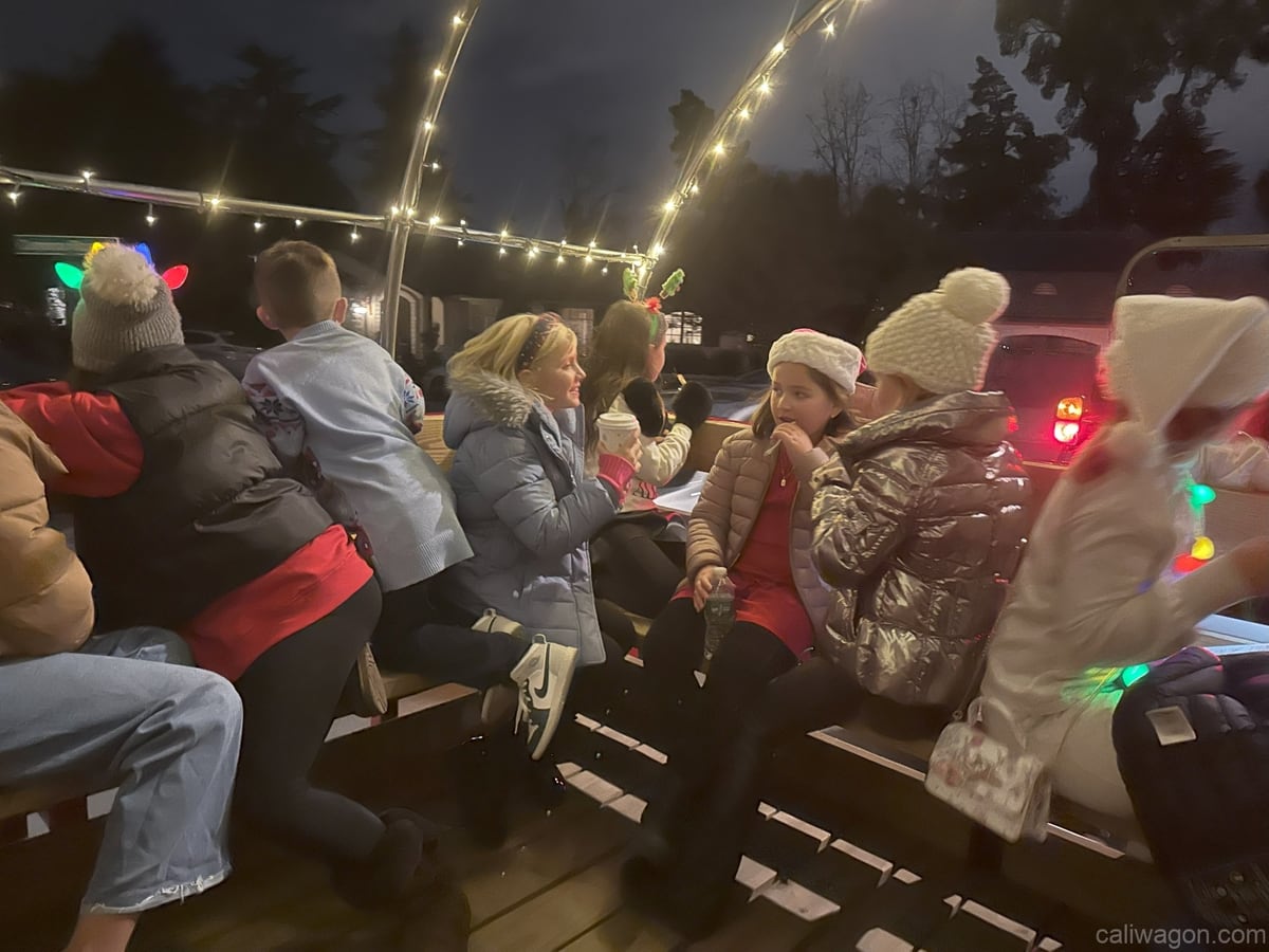 Riders aboard the Cali Wagon under lit hoops on a decorated Willow Glen street, December 2024 (photo 6 of 81)
