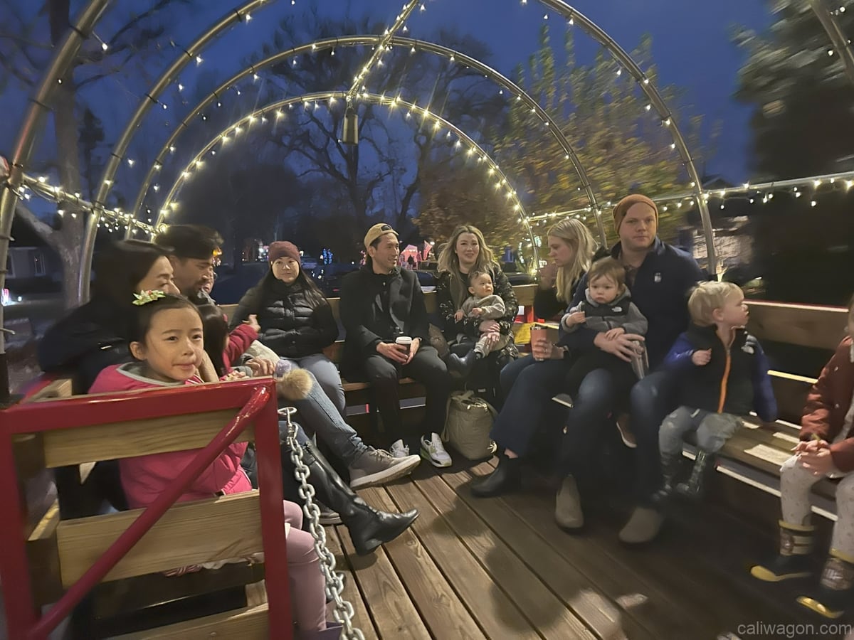 Riders aboard the Cali Wagon under lit hoops on a decorated Willow Glen street, December 2024 (photo 9 of 81)