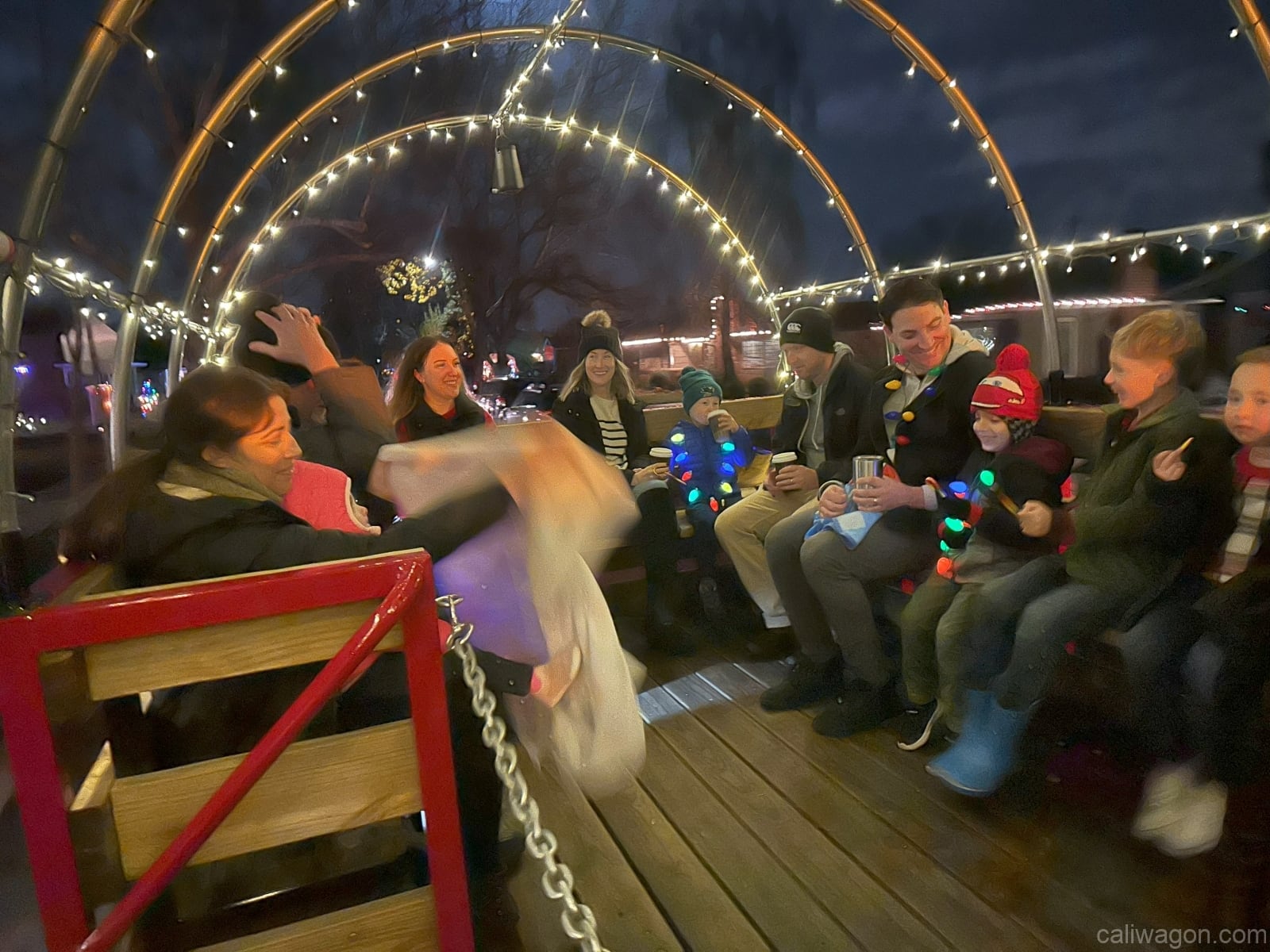 Riders aboard the Cali Wagon under lit hoops on a decorated Willow Glen street, December 2024 (photo 12 of 81)