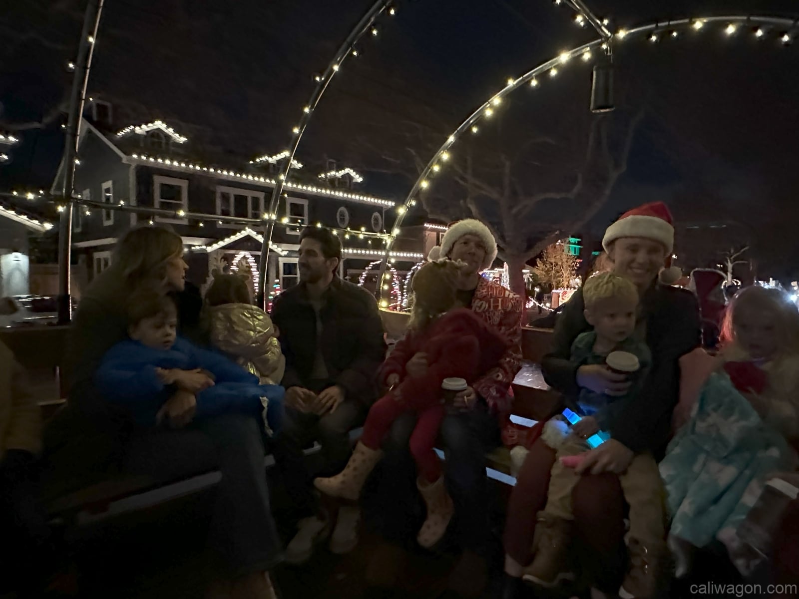 Riders aboard the Cali Wagon under lit hoops on a decorated Willow Glen street, December 2024 (photo 13 of 81)