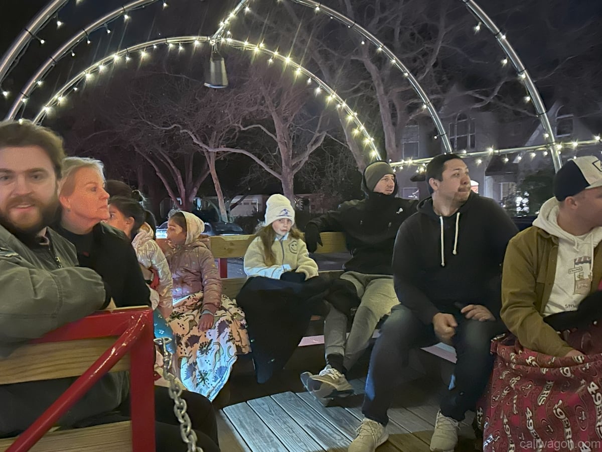 Riders aboard the Cali Wagon under lit hoops on a decorated Willow Glen street, December 2024 (photo 35 of 81)