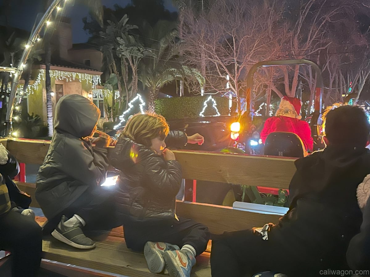 Riders aboard the Cali Wagon under lit hoops on a decorated Willow Glen street, December 2024 (photo 37 of 81)