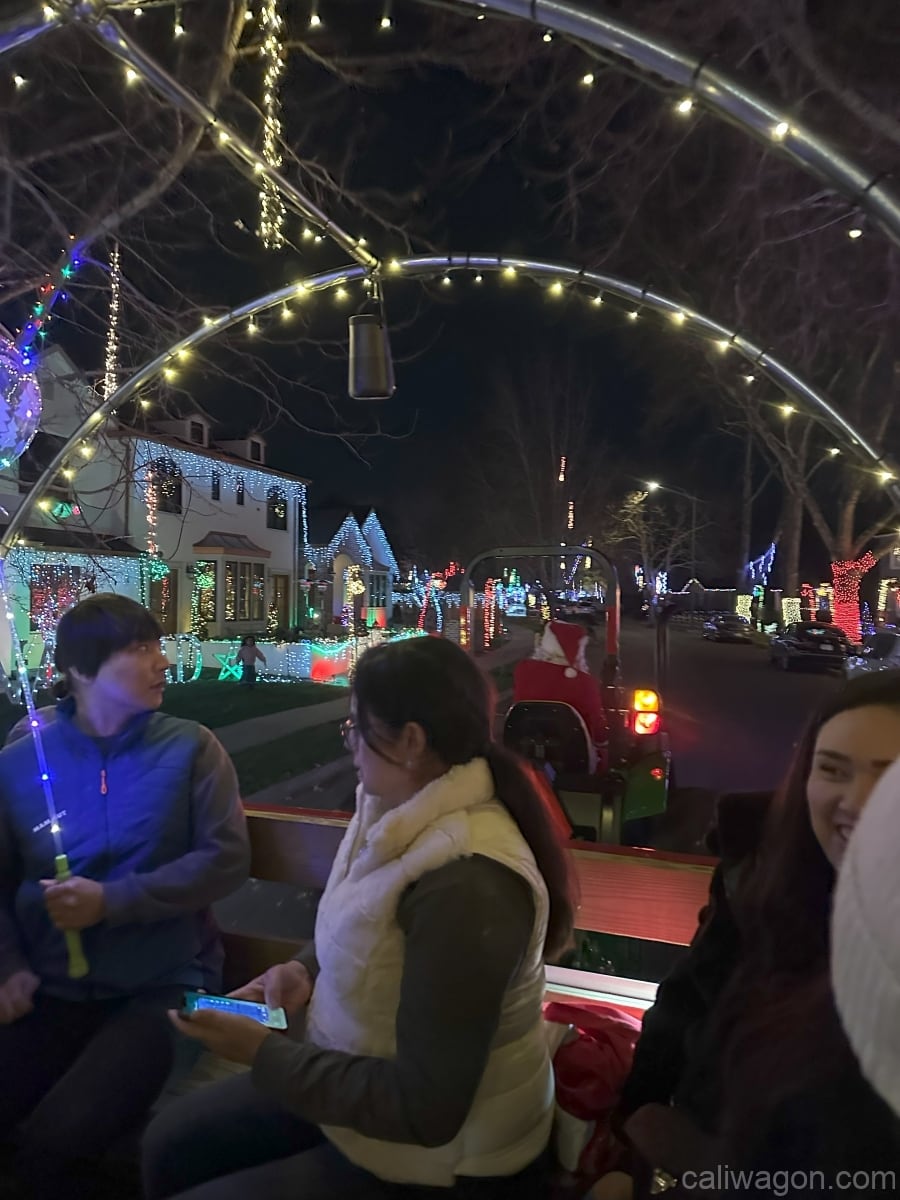 Riders aboard the Cali Wagon under lit hoops on a decorated Willow Glen street, December 2024 (photo 36 of 81)