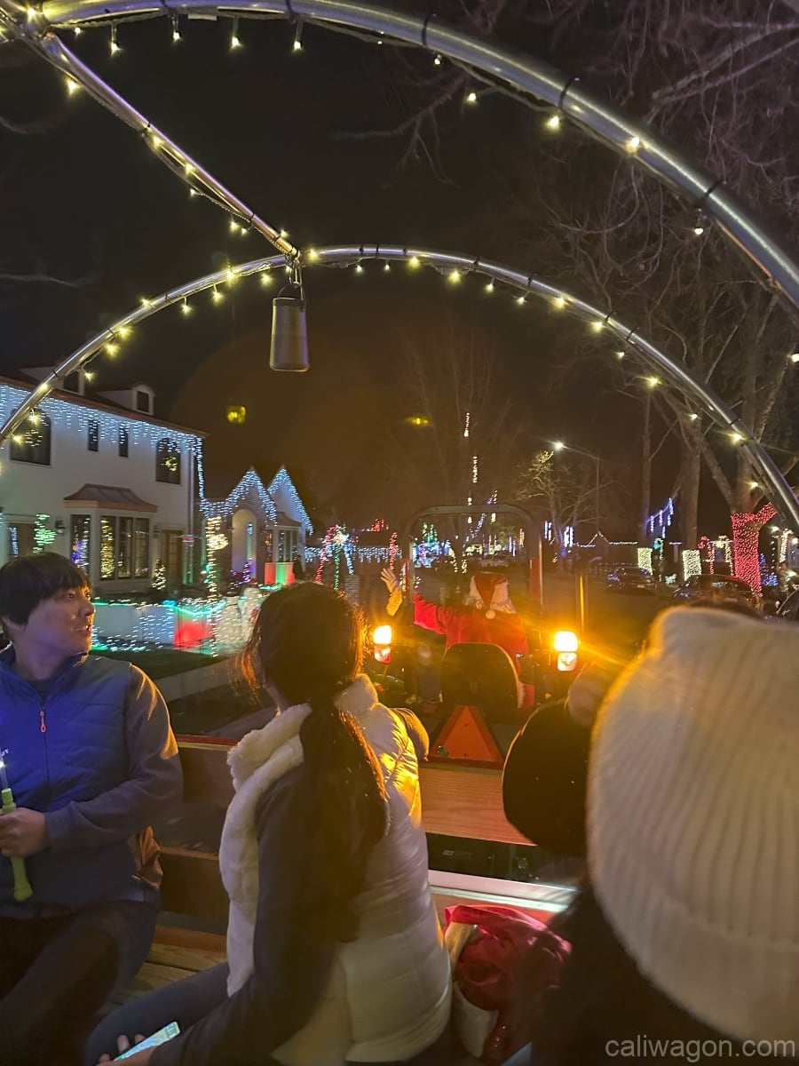 Riders aboard the Cali Wagon under lit hoops on a decorated Willow Glen street, December 2024 (photo 40 of 81)