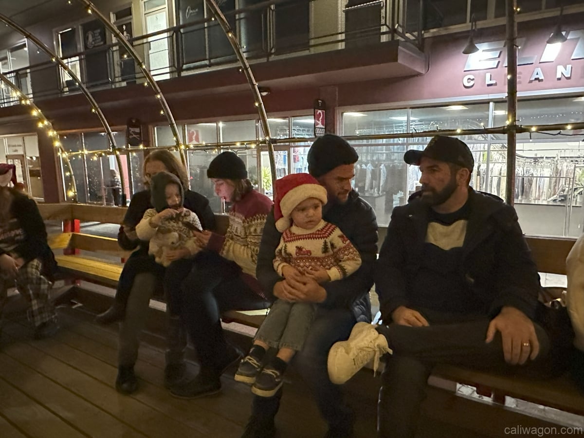 Riders aboard the Cali Wagon under lit hoops on a decorated Willow Glen street, December 2024 (photo 43 of 81)