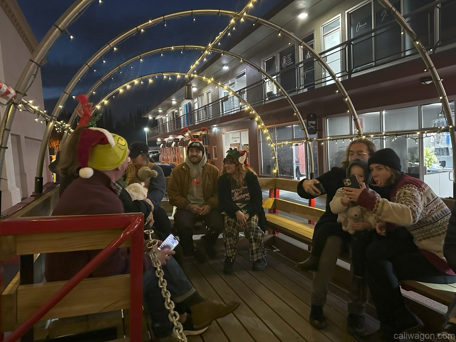 Riders aboard the Cali Wagon under lit hoops on a decorated Willow Glen street, December 2024 (photo 45 of 81)