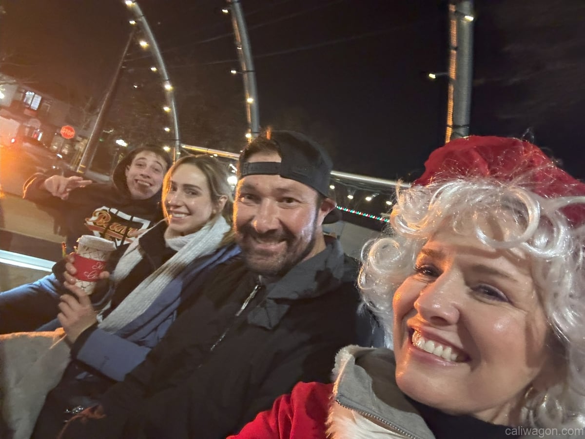 Riders aboard the Cali Wagon under lit hoops on a decorated Willow Glen street, December 2024 (photo 50 of 81)
