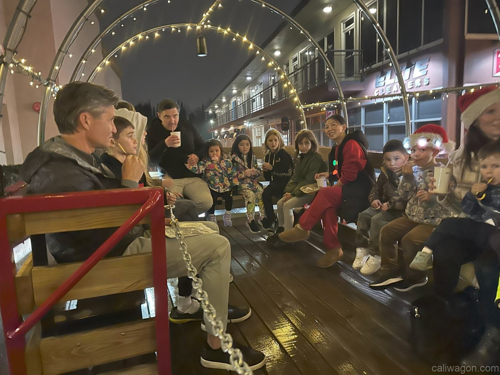 Riders aboard the Cali Wagon under lit hoops on a decorated Willow Glen street, December 2024 (photo 56 of 81)