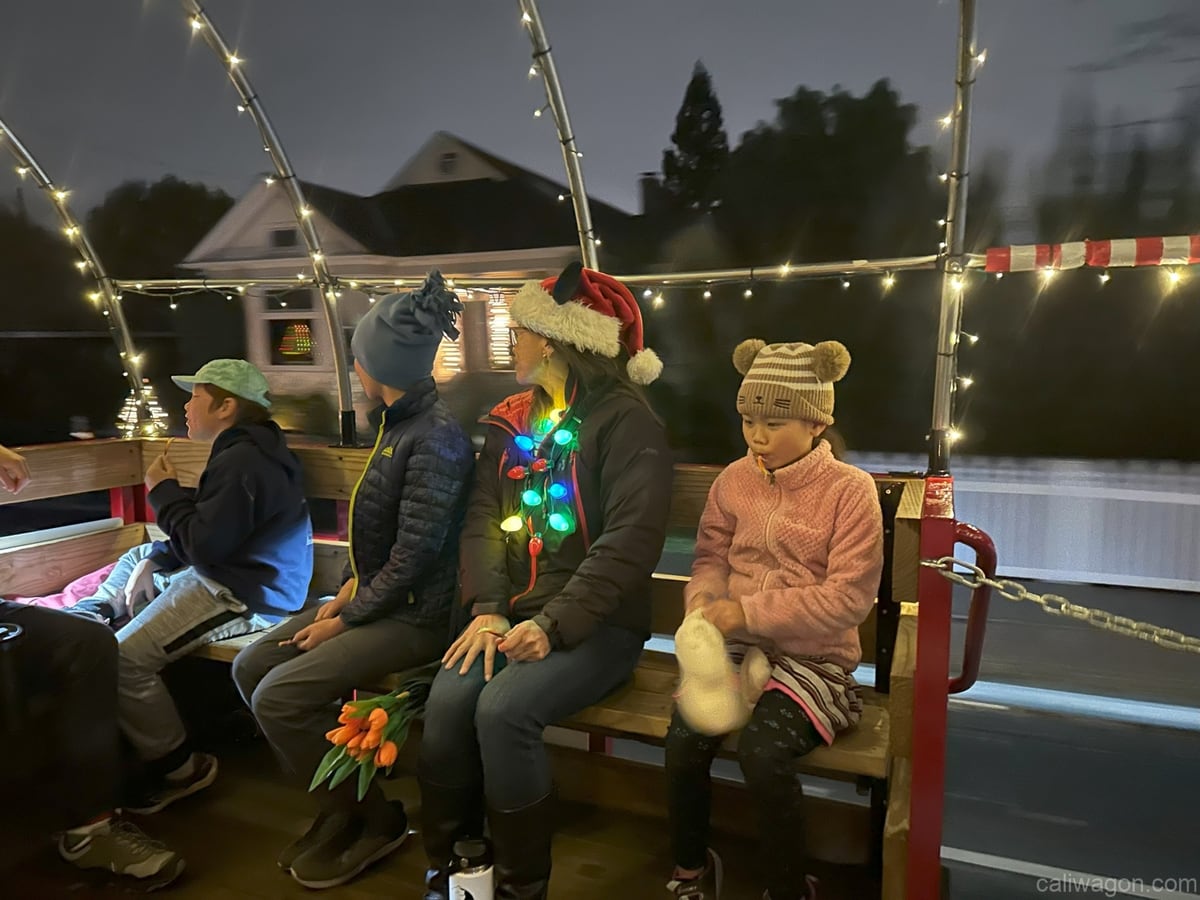 Riders aboard the Cali Wagon under lit hoops on a decorated Willow Glen street, December 2024 (photo 57 of 81)