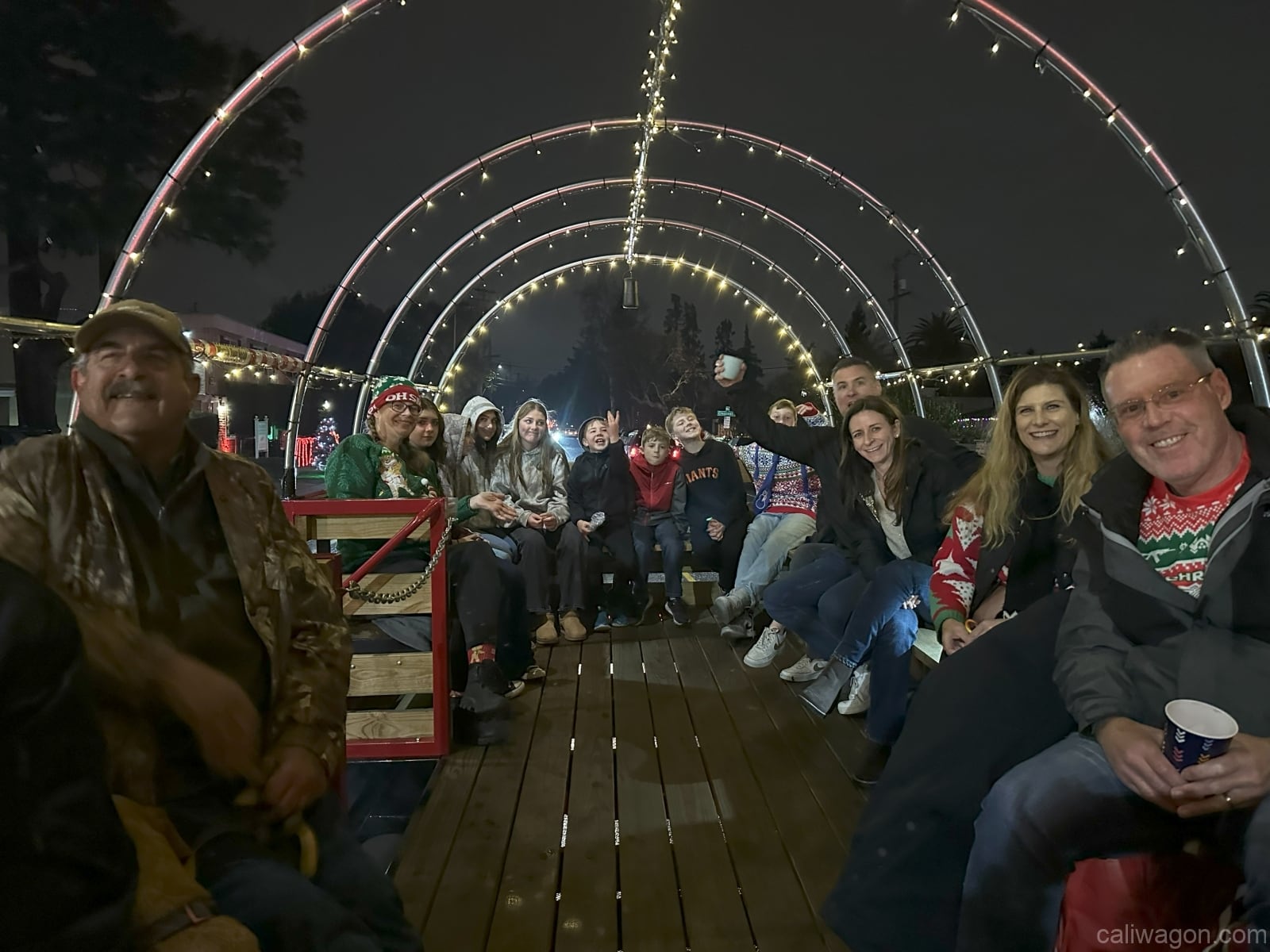 Riders aboard the Cali Wagon under lit hoops on a decorated Willow Glen street, December 2024 (photo 59 of 81)