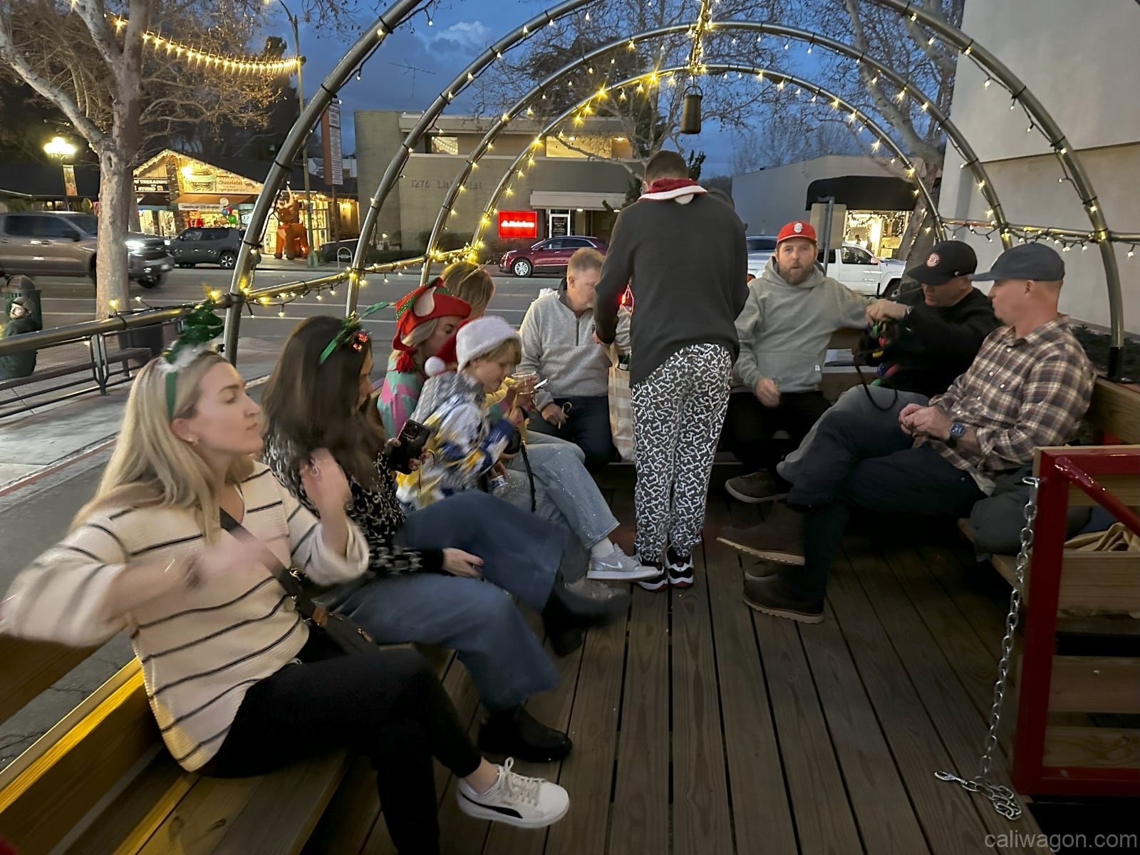 Riders aboard the Cali Wagon under lit hoops on a decorated Willow Glen street, December 2024 (photo 65 of 81)