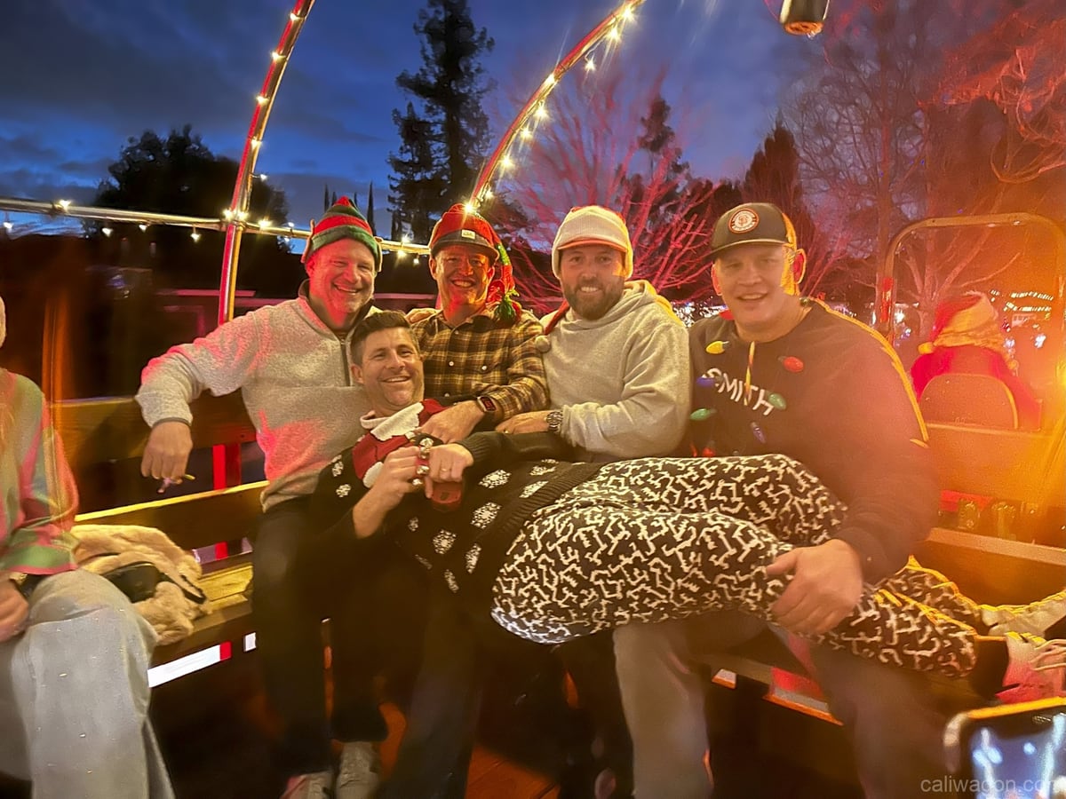 Riders aboard the Cali Wagon under lit hoops on a decorated Willow Glen street, December 2024 (photo 72 of 81)