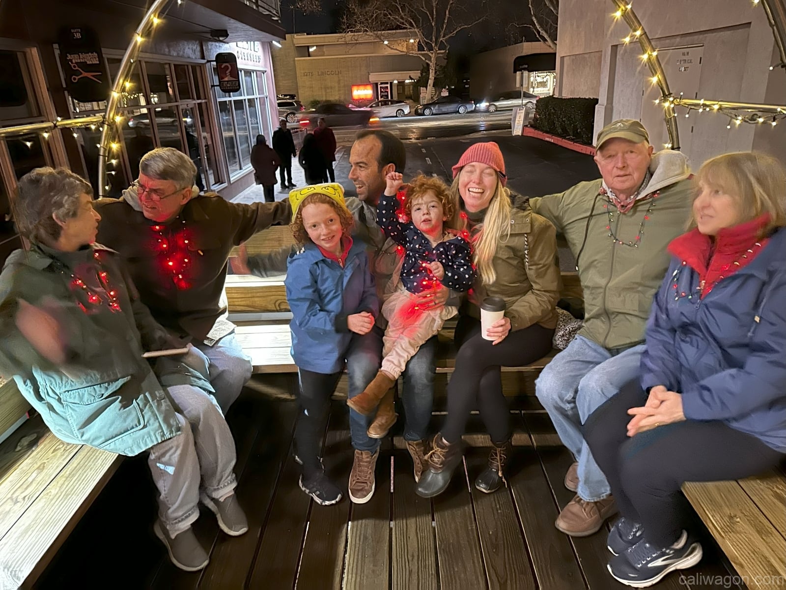 Riders aboard the Cali Wagon under lit hoops on a decorated Willow Glen street, December 2024 (photo 73 of 81)