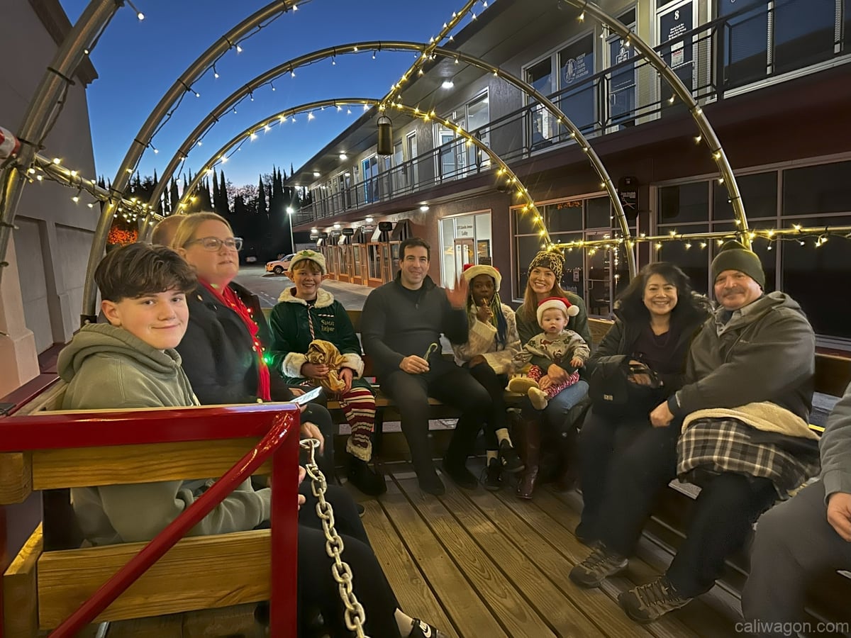 Riders aboard the Cali Wagon under lit hoops on a decorated Willow Glen street, December 2024 (photo 34 of 81)