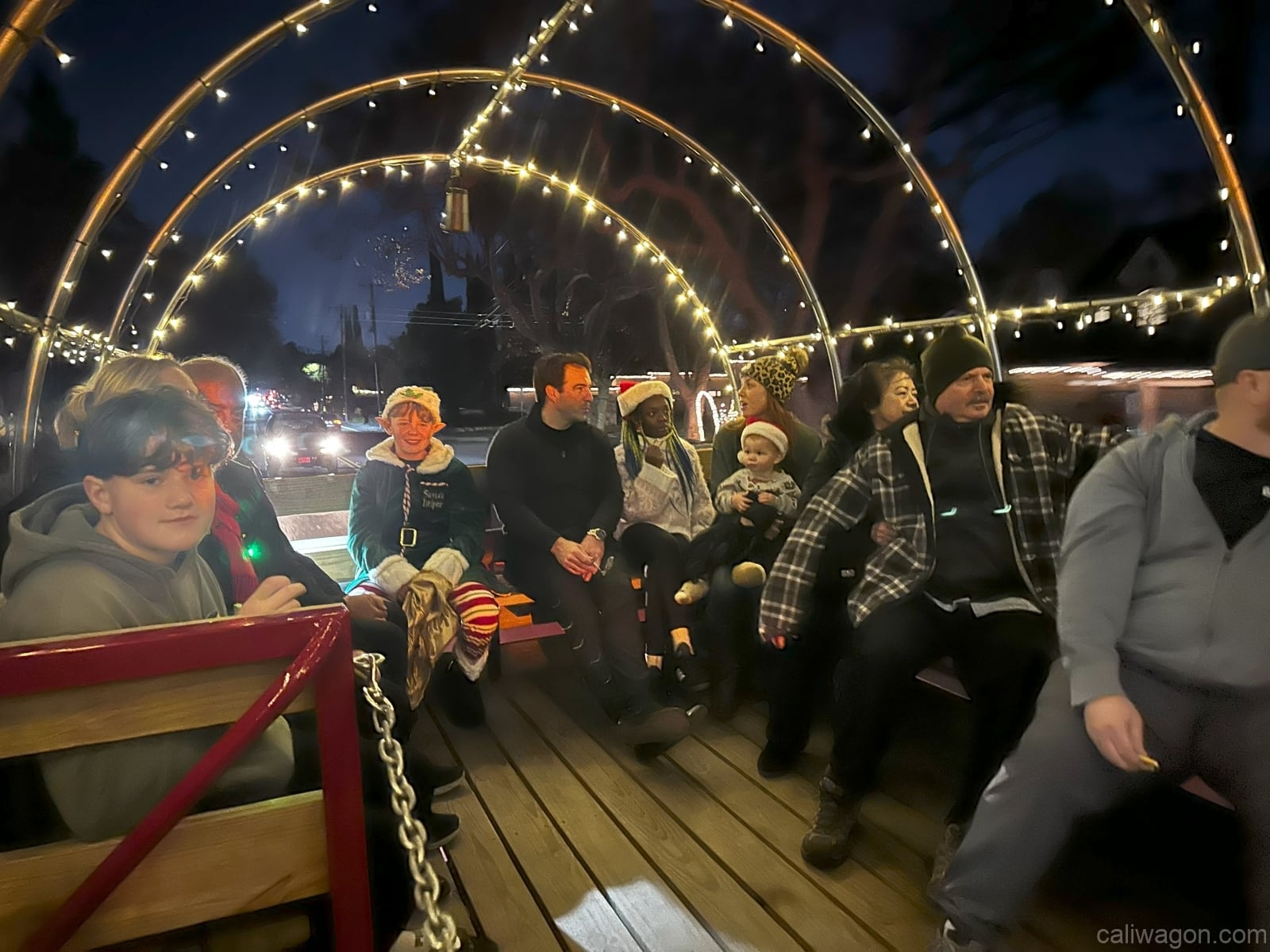 Riders aboard the Cali Wagon under lit hoops on a decorated Willow Glen street, December 2024 (photo 29 of 81)